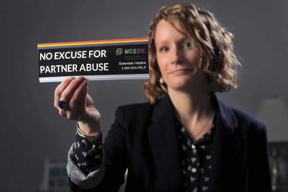 Regina Rooney, communications director for the Maine Coalition to End Domestic Violence, holds up a sign saying "No excuse for partner abuse."